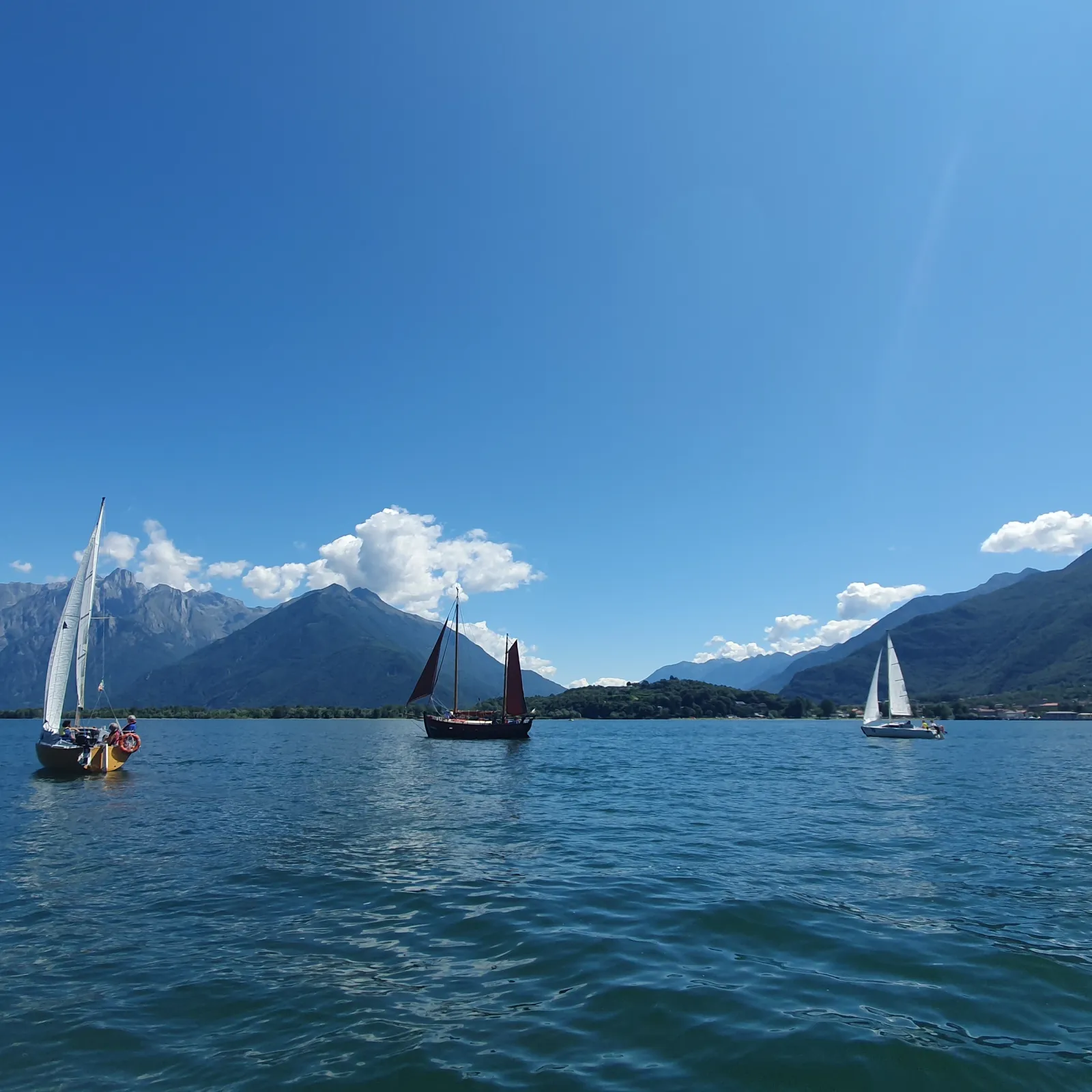 Cabinati a vela in navigazione sul Lago di Como, davanti alle montagne